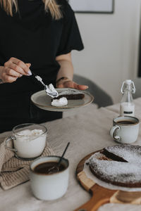 Woman adding whipped cream to chocolate cake