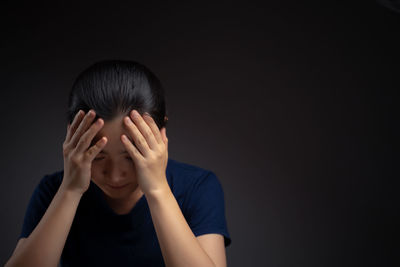 Close-up portrait of a teenage girl over black background