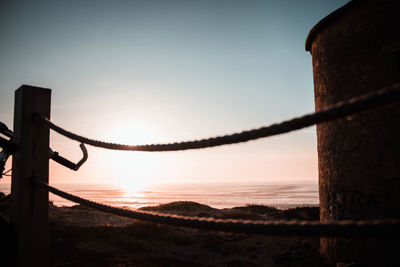 Silhouette of wooden post on beach against sky during sunset