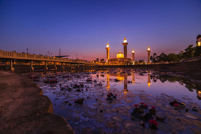 Reflection of illuminated buildings in water at sunset