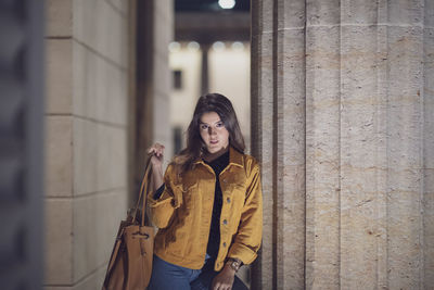 Portrait of young woman standing by architectural column