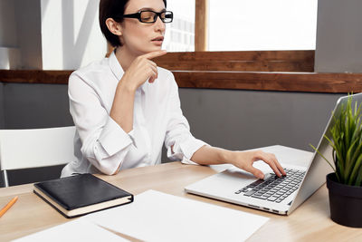 Young woman using mobile phone while sitting on table