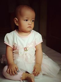 Cute baby girl sitting on bed at home