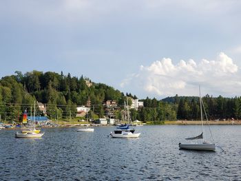 Sailboats moored on sea against sky