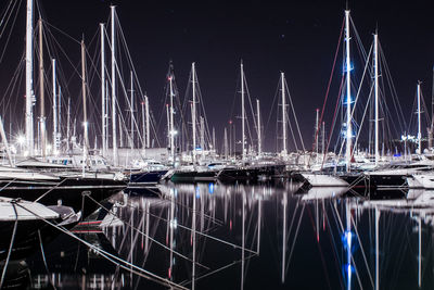 Illuminated sailboats moored at harbor against clear sky at night