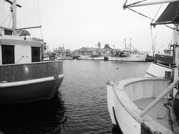 Boats moored at harbor against clear sky