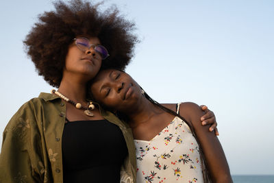 Happy young african american female best friends embracing each other while spending summer vacation together on seashore