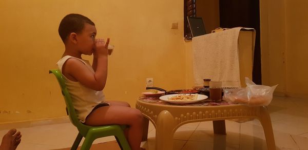 Boy sitting on table at home