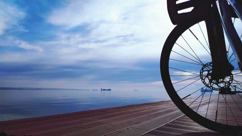 Bicycle by sea against sky