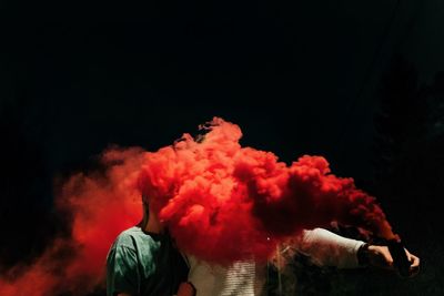 Young man smoking against black background