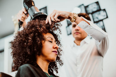 Low angle view of barber drying woman hair in salon