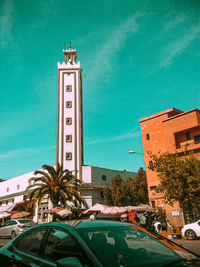 Clock tower by building against sky in city