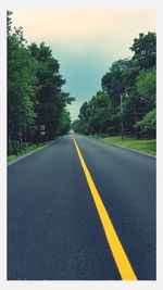 Empty road with trees in background