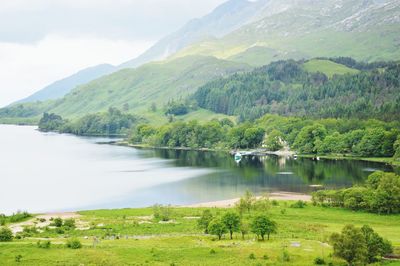 Scenic view of lake by mountains against sky