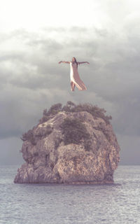 Surreal full length view of woman flying over sea