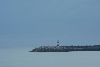 Lighthouse by sea against sky