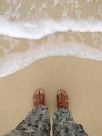 Low section of man standing on beach