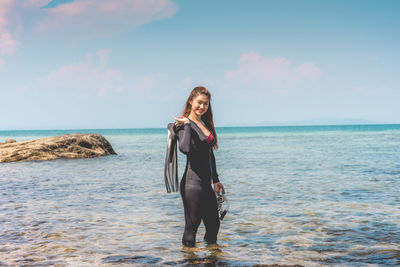 Woman standing in sea against sky