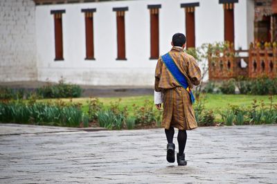 Rear view of man in traditional clothing walking on street