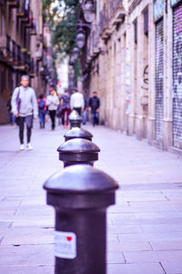 Rear view of woman walking on footpath by street in city