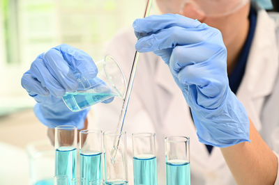 Midsection of scientist examining chemical in laboratory