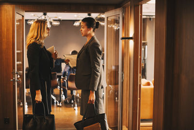 Side view of female legal colleagues discussing at office corridor