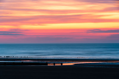 Scenic view of sea against dramatic sky during sunrise