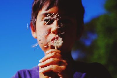 Close-up of boy blowing dandelion seeds