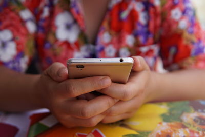 Midsection of child using mobile phone on table