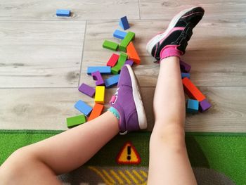 Low section of girl playing with colorful toys on hardwood floor