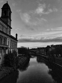 Bridge over river by buildings in city against sky