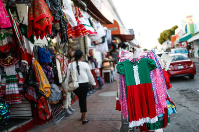 Rear view of woman walking on sidewalk by stores in market