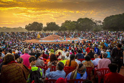 Group of people at music concert against sky during sunset