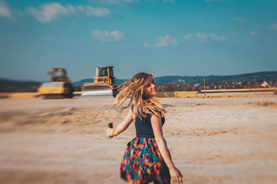 Young woman standing on land against sky