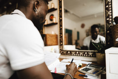 Male hairdresser calculating financial bill at table in barber shop