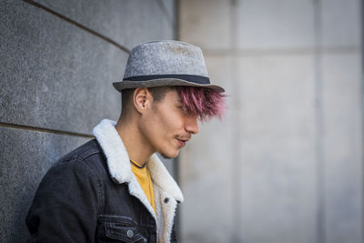 Portrait of young man standing against wall