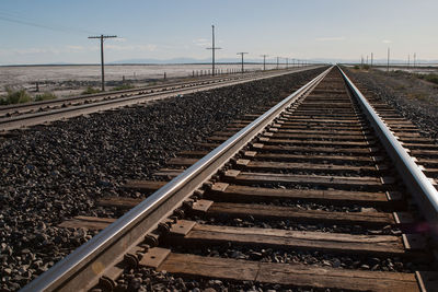 Railroad tracks by field against sky