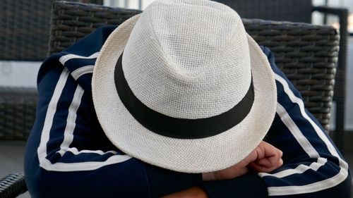 Rear view of person wearing hat sitting outdoors