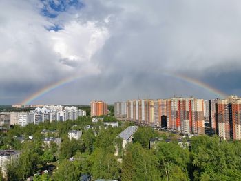 Rainbow over city buildings against sky