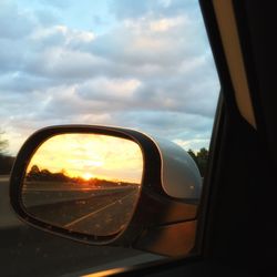 Close-up of side-view mirror at sunset