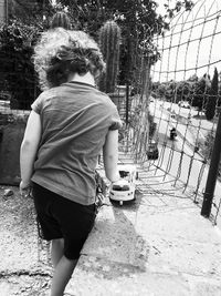 Rear view of boy with umbrella in city