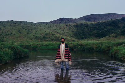 Man standing in lake against sky during sunset