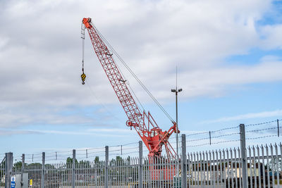 Low angle view of cranes at construction site against sky