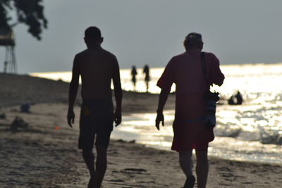 Rear view of silhouette people walking on beach