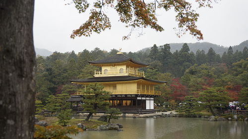 Built structure by lake and trees against sky