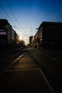 Empty road by buildings in city against sky