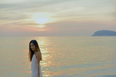 Woman standing on beach at sunset