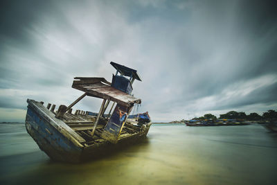 Abandoned ship in sea against sky