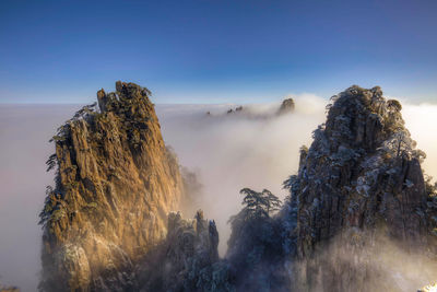 Rock formations by cloudscape against sky