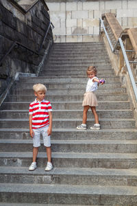 Full length of cute sibling standing on staircase